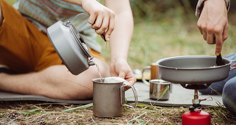 42657664 - two fellow campers making tea and preparing food in the forest